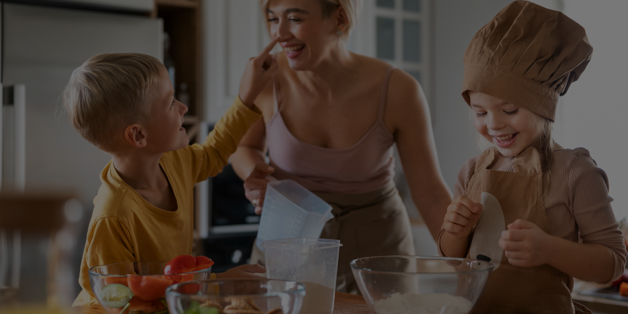 Woman and two children in a kitchen preparing food together.