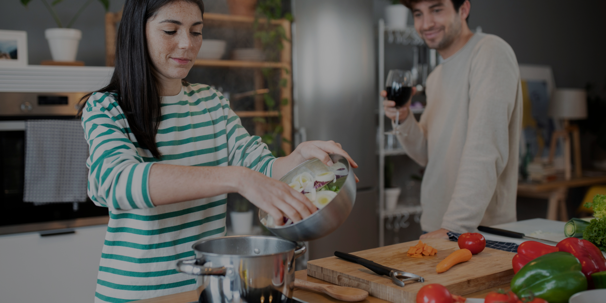 Woman preparing food in a kitchen with a man in the background

